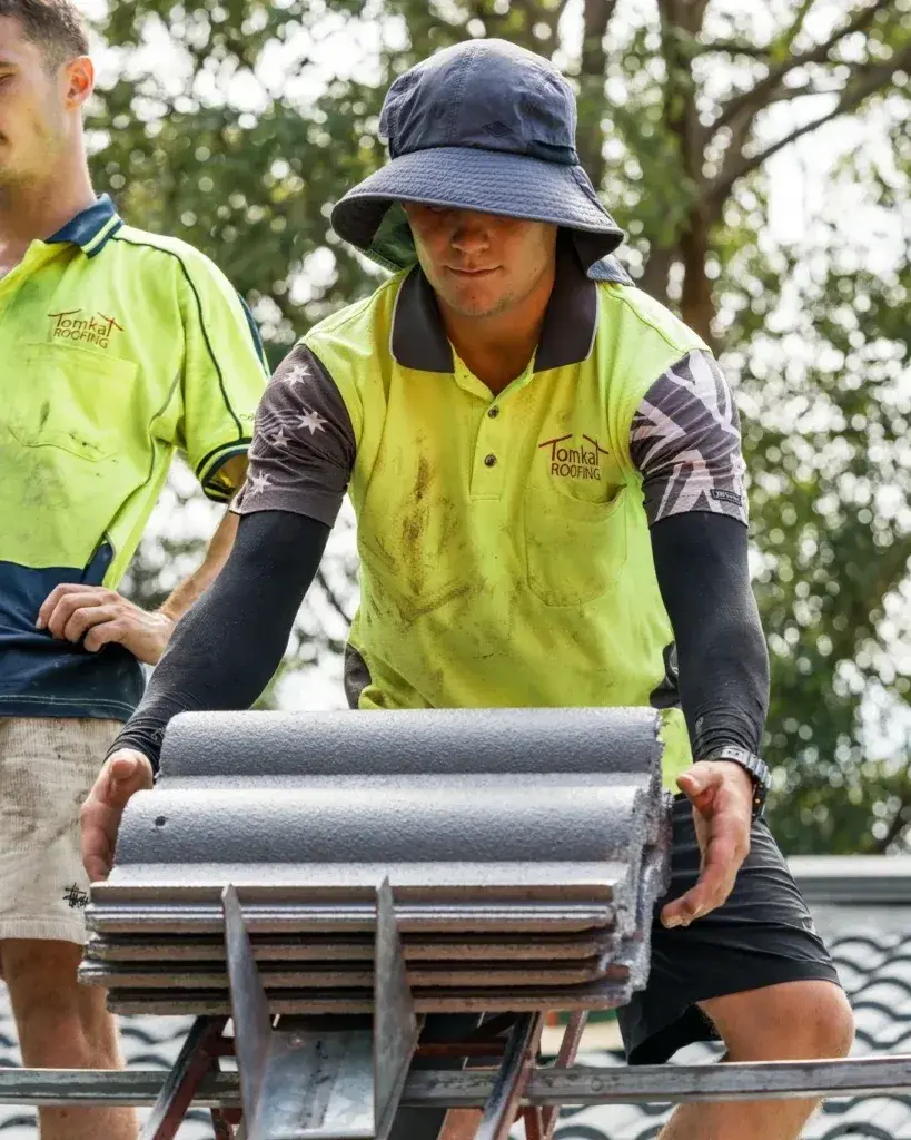 Roofing contractor repairing broken roof tiles and flashing during roof repair service.