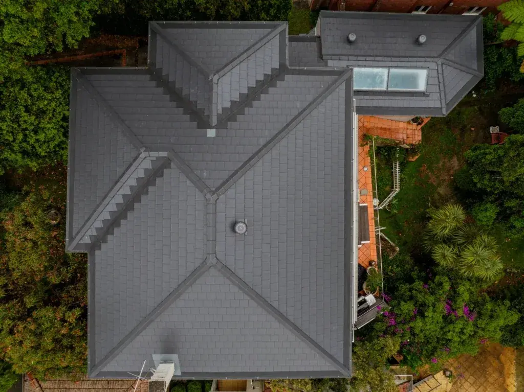 Licensed Tomkat Roofing specialist replacing a cracked terracotta tile on a Sydney residential property using professional safety equipment and matching replacement tiles.