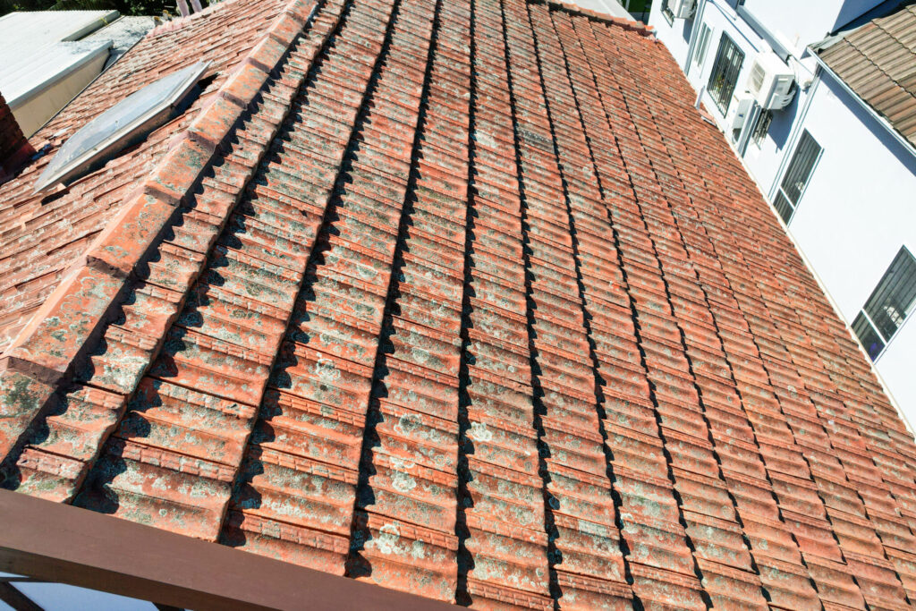 Hail damage on a Sydney roof showing cracked tiles and dented ridge capping after a storm.